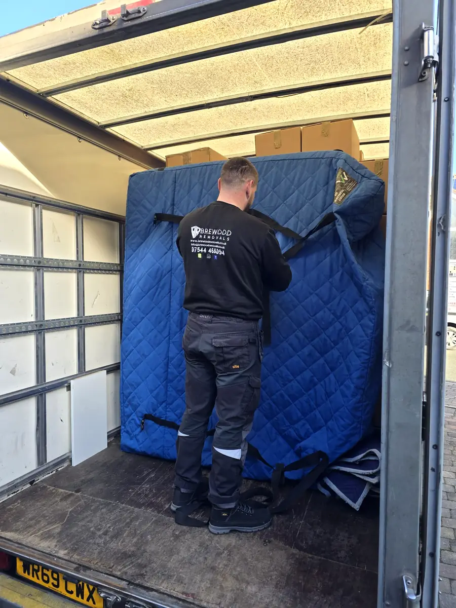 Brewood Removals crew strapping blanket-wrapped furniture inside the van